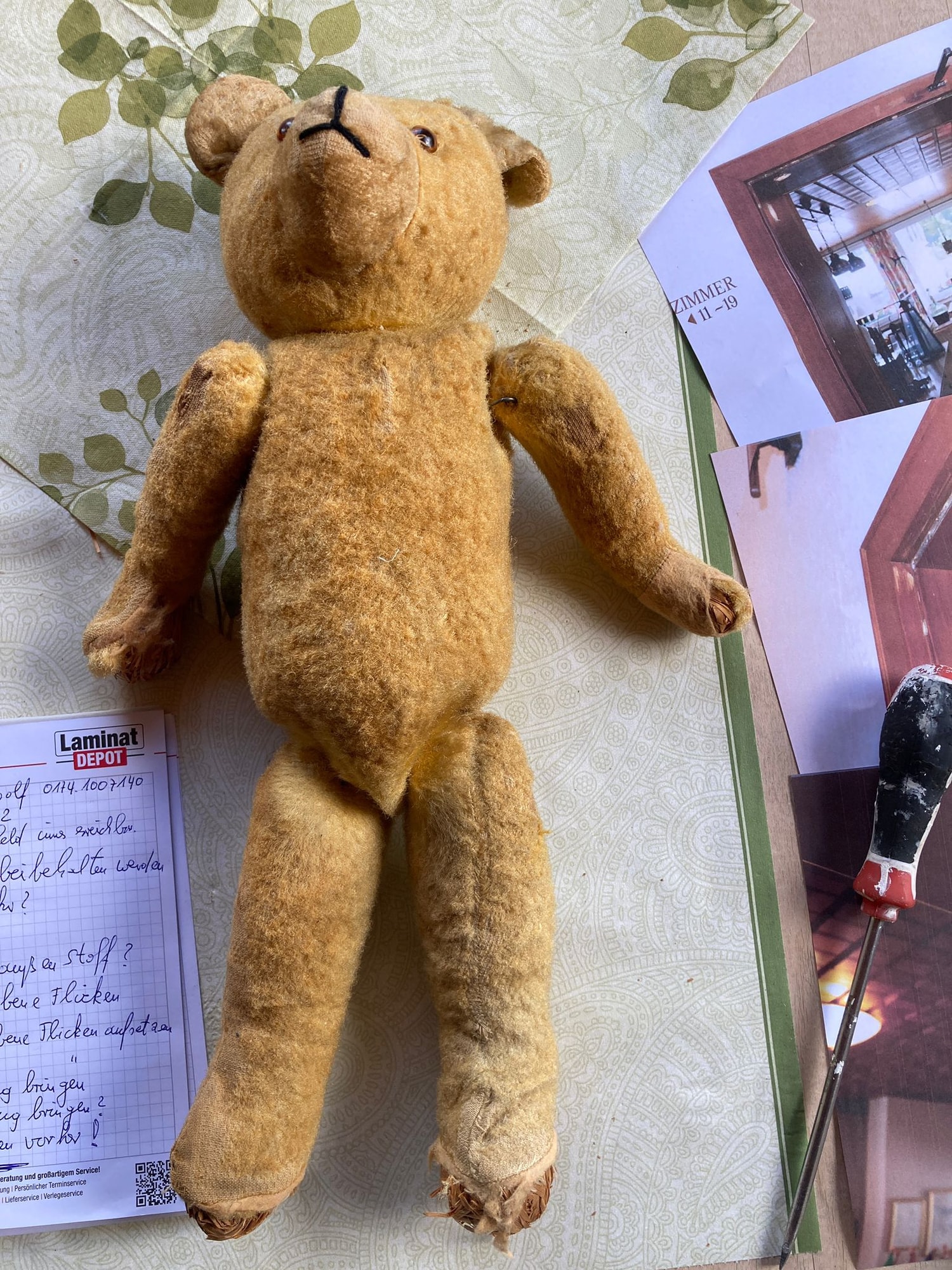 Antiker Teddybär vor der Restaurierung mit Notizen und Werkzeug