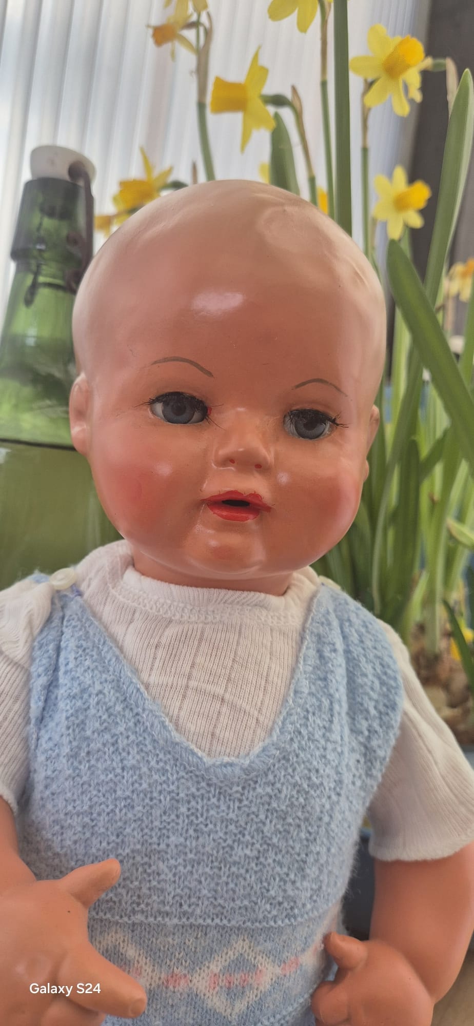 Babypuppe mit blauen Augen und Strickweste nach Puppenreparatur